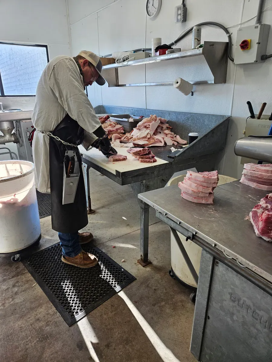 Howard Larson hand-cutting fresh pork at H&M Custom Meat's processing facility in Creston, WA